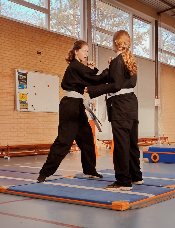 Go Selfdefense voor meiden twee meisjes in een gymzaal die budo training krijgen